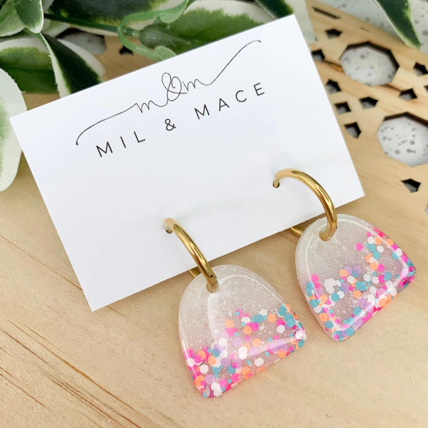 Arches Resin Earrings in White with pink, blue, orange and white speckles. They have a gold huggie closure