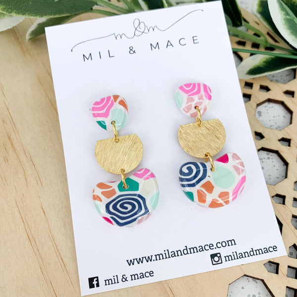 Lolly Floral Dangle Clay Earrings with a pink, green, navy and orange floral design. They have a stud closure