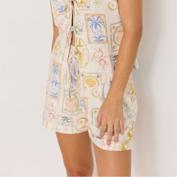 Close up of the beautiful resort inspired print featuring illustrations of palm trees, shells, sun against a cream coloured base. 