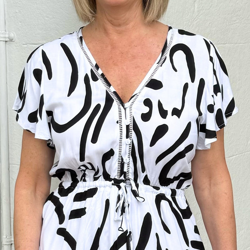 Close up of the bodice area which features functional buttons, crochet detailing along the neckline extending to the bodice and a drawstring waist.