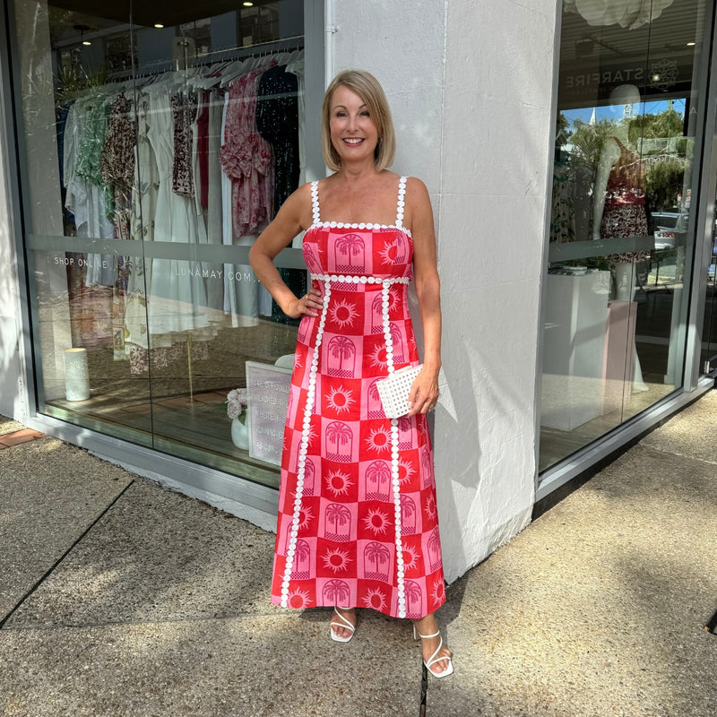 Our Verity Bow Dress has a red and pink tropical inspired print with white embroidery accents.