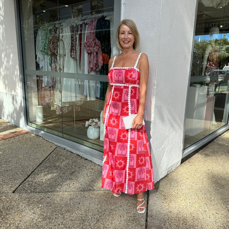 The dress has white embroidery straps and the embroidery detailing extends across the bodice and vertically down the skirt.