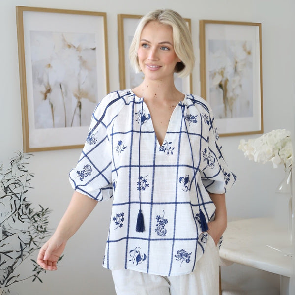 Our Jayde Top has embroidered navy accents against a white base.