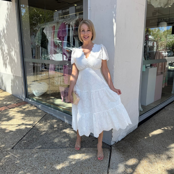 The dress has a scalloped V neckline, gather detailing under the bust and it falls into a midi length skirt.