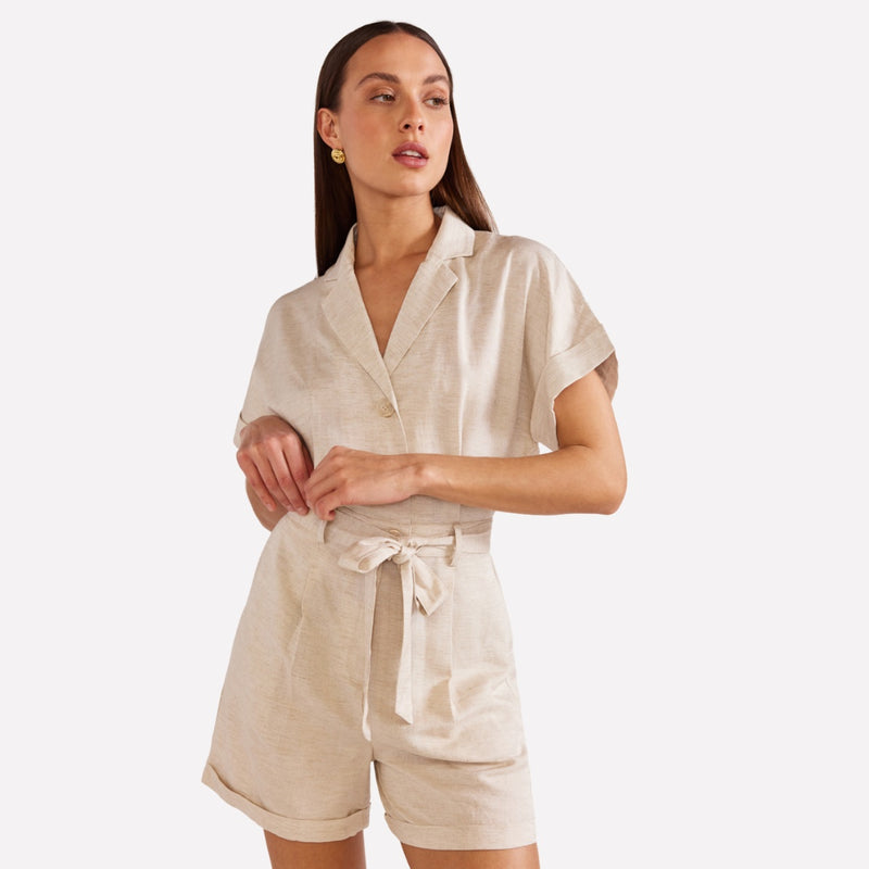 The playsuit features a collar, button bodice, self tie belt, zip closure on the short, side pockets and cuff hems on the shorts