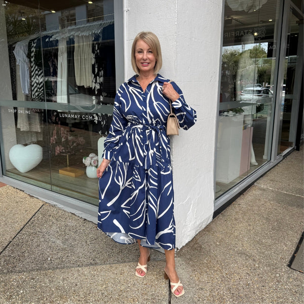 This shirt dress features a collar, button front, long sleeves and a curved hem.