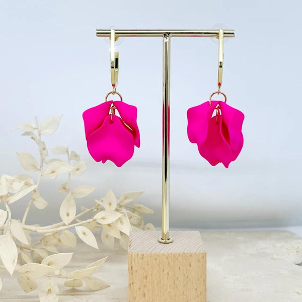 These earrings have a stud closure and feature fuchsia pink petals suspended from a gold hoop