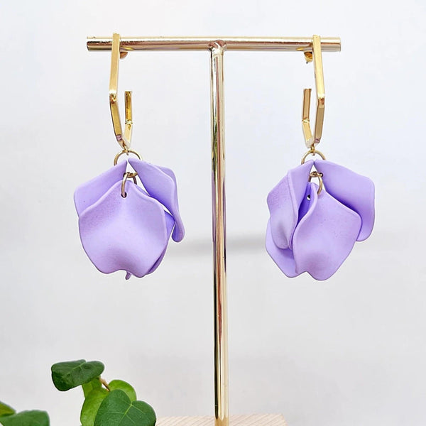 These earrings have lilac coloured petals suspended from a gold hexagonal hoop with stud closure