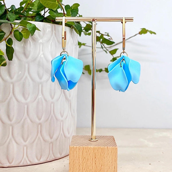 These earrings have sky blue petals suspended from a gold hexagonal hoop