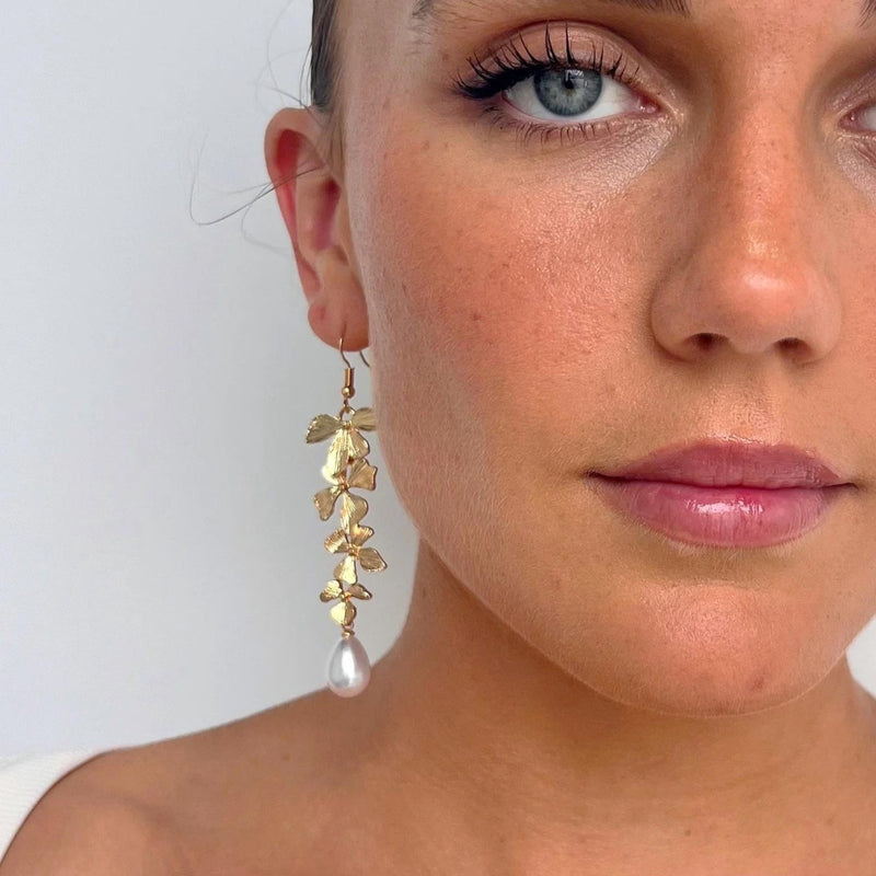 These beautiful drop earrings feature gold flowers with a faux pearl suspended and hook closure