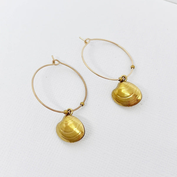 The earrings have a lovely shell charm suspended from a thin gold hoop.