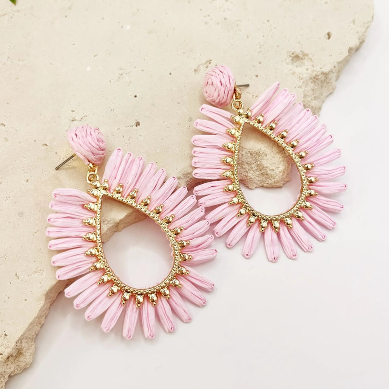 These teardrop shaped earrings have a pink raffia edge and gold accents with a stud back closure.