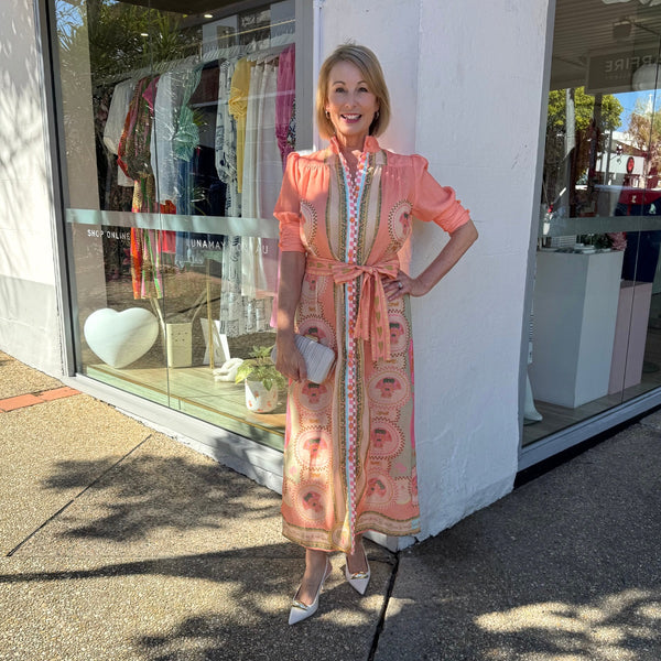 Features a mock collar, short sleeves, self print waist tie and a maxi length skirt.