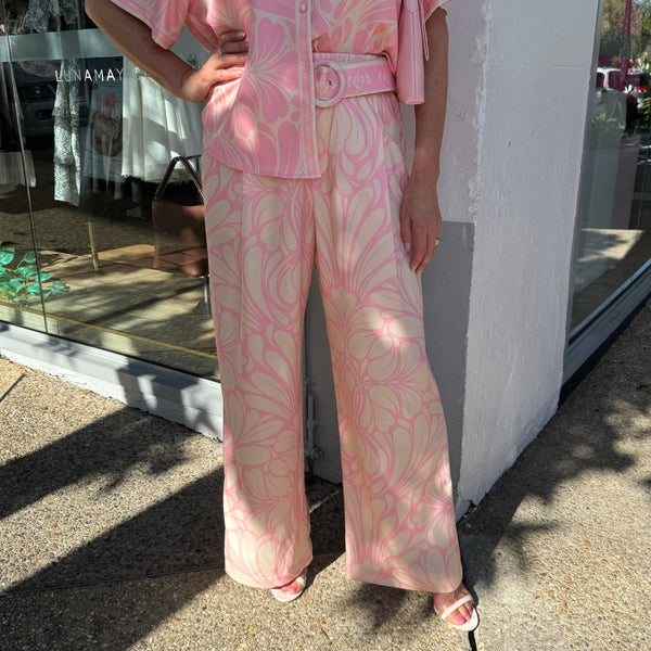 Our Jovana Pants have a pink and cream floral print and feature a button and zip fastening, belt loops and a self print belt