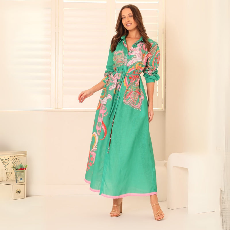 Our La Palma Dress has a bold green base with a multi coloured floral and paisley print. It features a collar, long sleeves and a maxi length skirt.