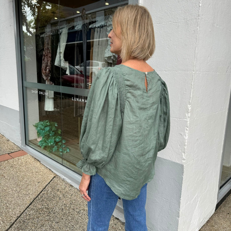 Side view of the top which has a curved, dipped back hem